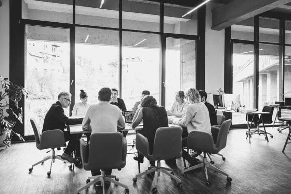 A large conference room with about a dozen employees gathered around the table.