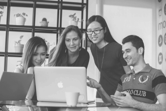 Four colleagues looking at the same screen and discussing their work, highlighting the unique advantages of small business culture.