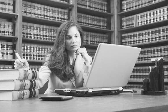 A legal assistant working in a law library, surrounded by law books.