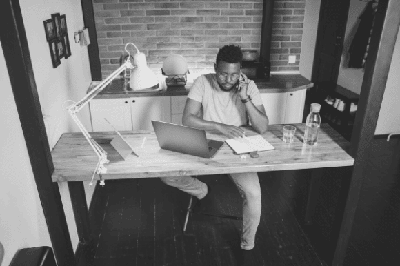 A hiring manager sitting at his home office desk who knows how to conduct a phone interview is screening a potential new hire.