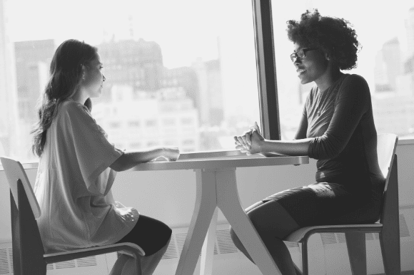 Manager asking a job candidate the top behavioral interview questions at a table.