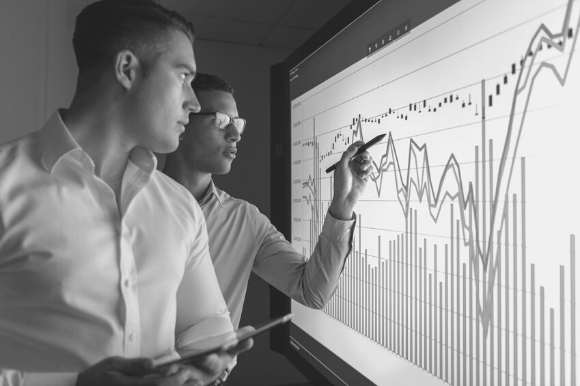 A business analyst and his colleague go over sales numbers.