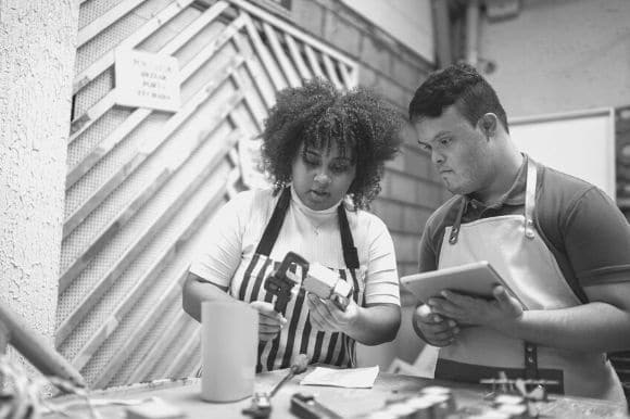 Developmentally disabled employee working with his manager to check products for quality.