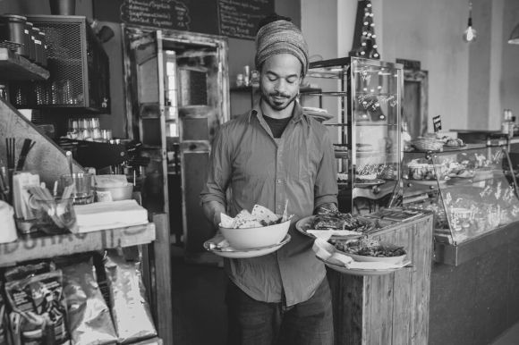 Restaurant server carrying bowls and dishes of food to customers.